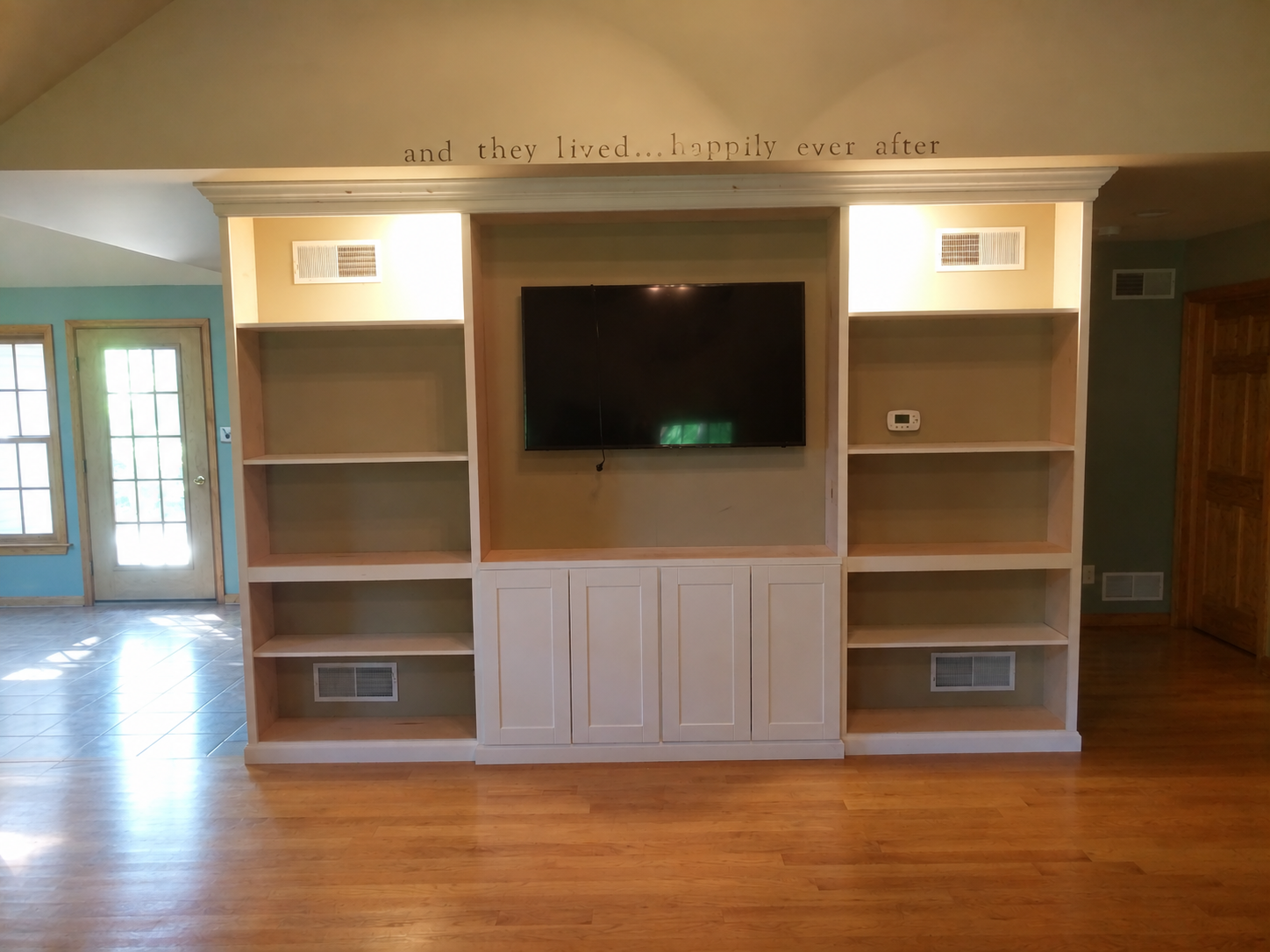 White built-in entertainment wall with shelving and fireplace-style center